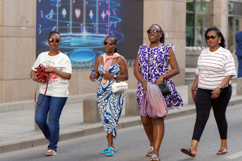 Four black women in varied casual styles walking on a city street
